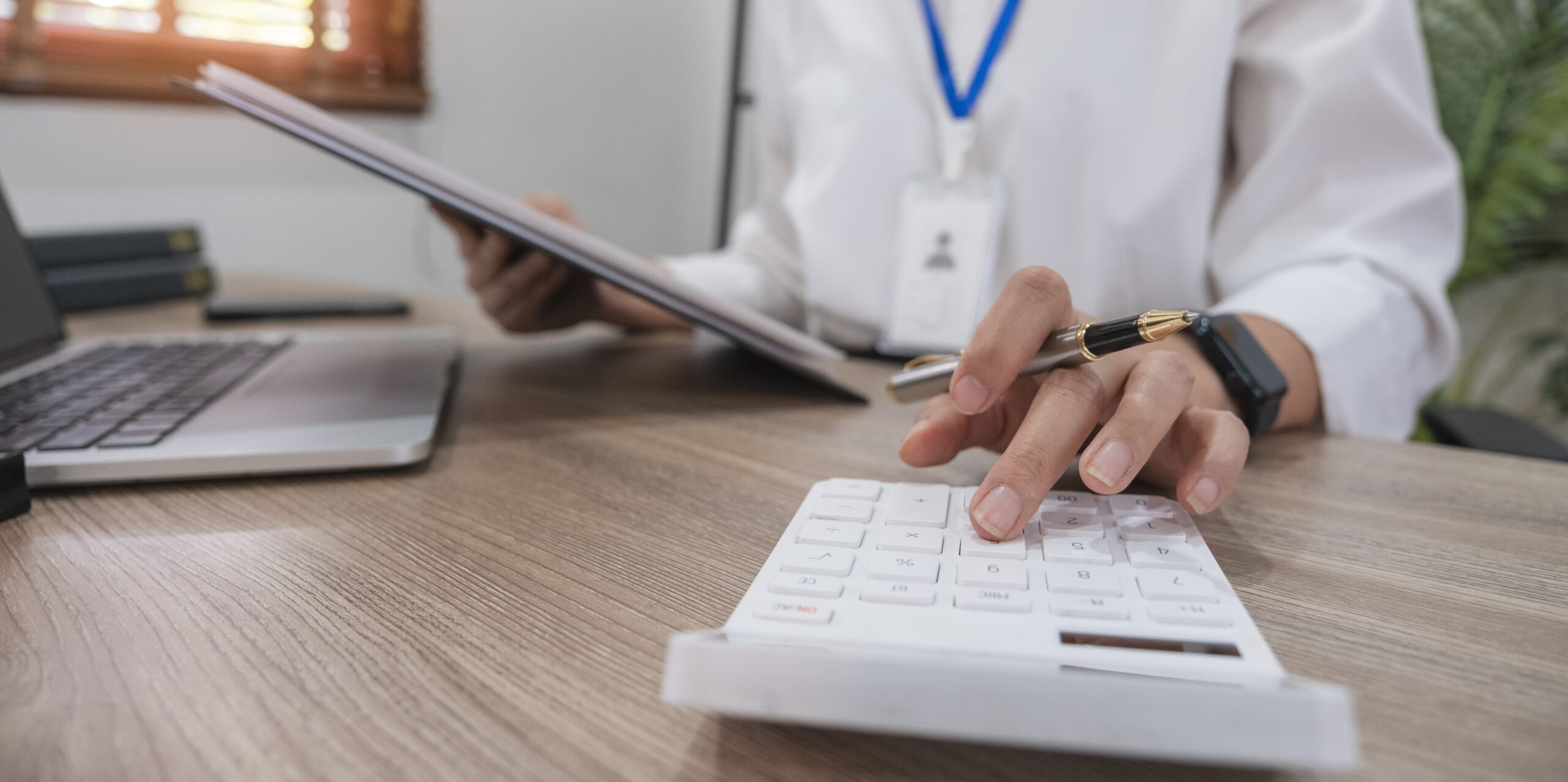 Close up Business woman using calculator and laptop for do math finance on wooden desk in office and business working background, tax, accounting, statistics and analytic research concept