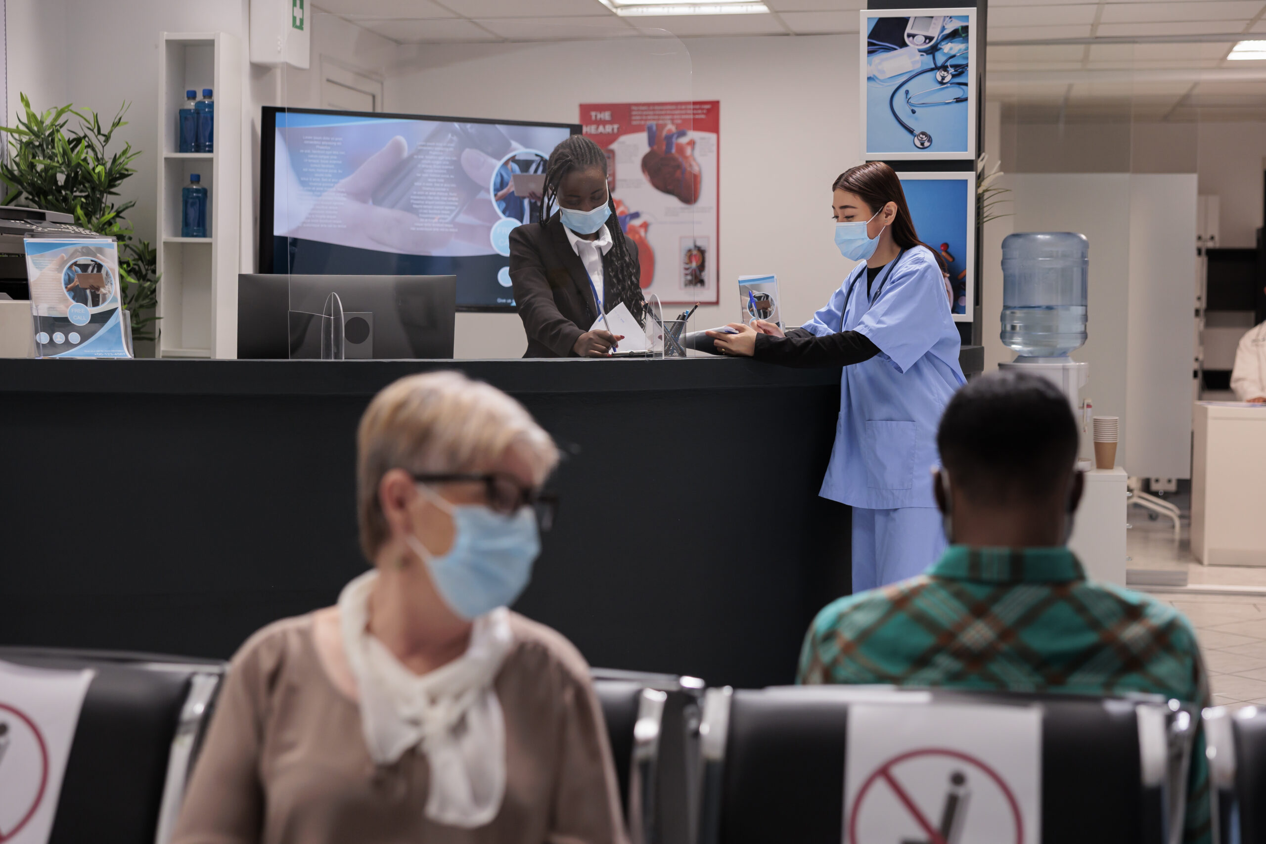 African american receptionist, asian nurse updating the patient list